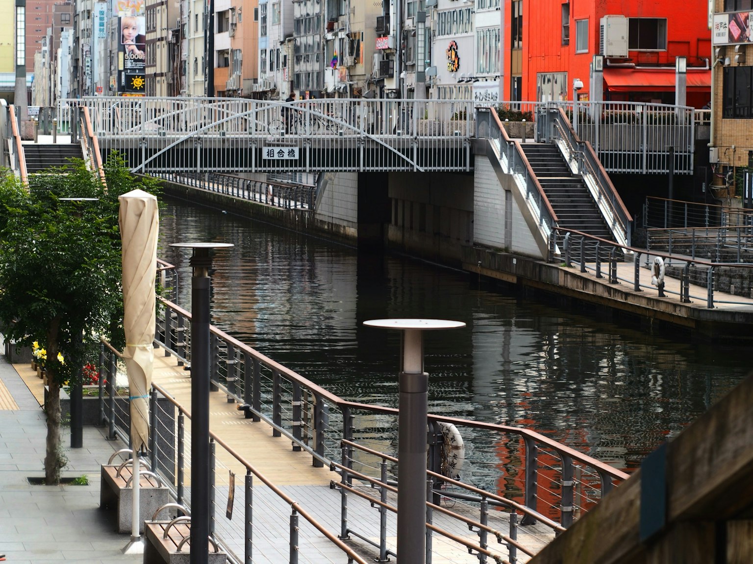 河边步道和桥的风景，桥上有行人通道，周围有建筑和水