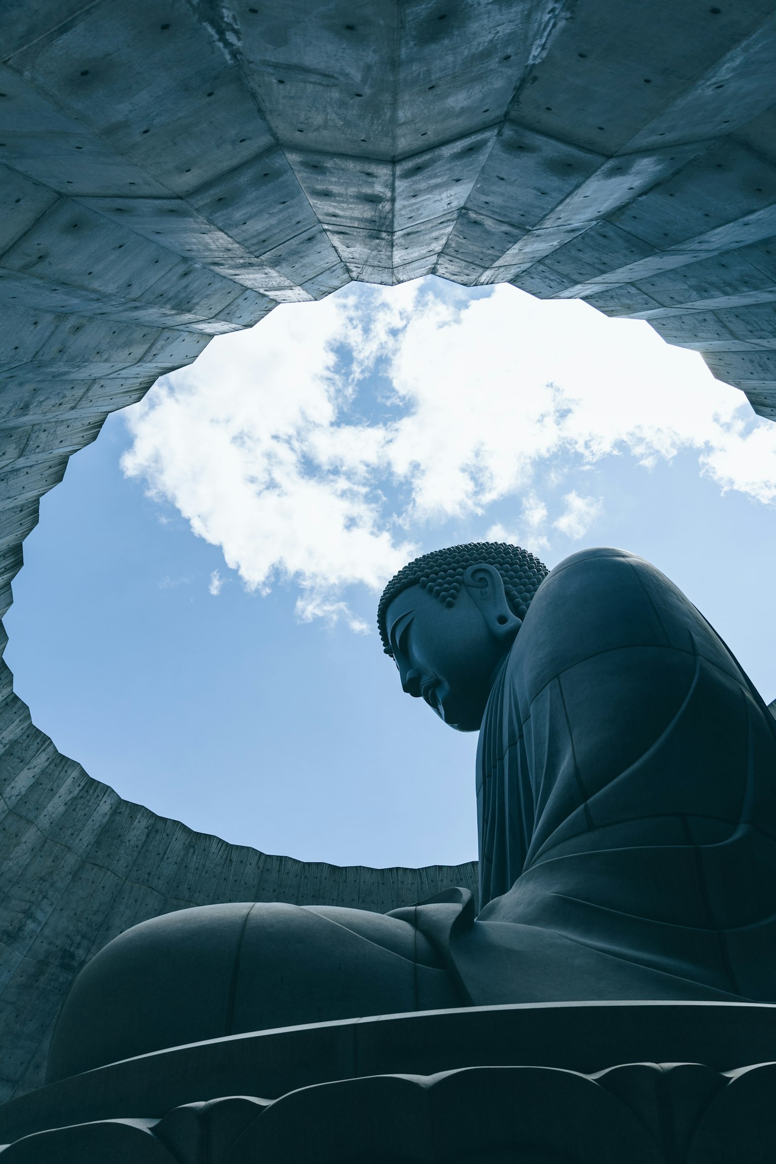 Silueta de una estatua de Buda contra un cielo azul brillante enmarcada por una estructura circular