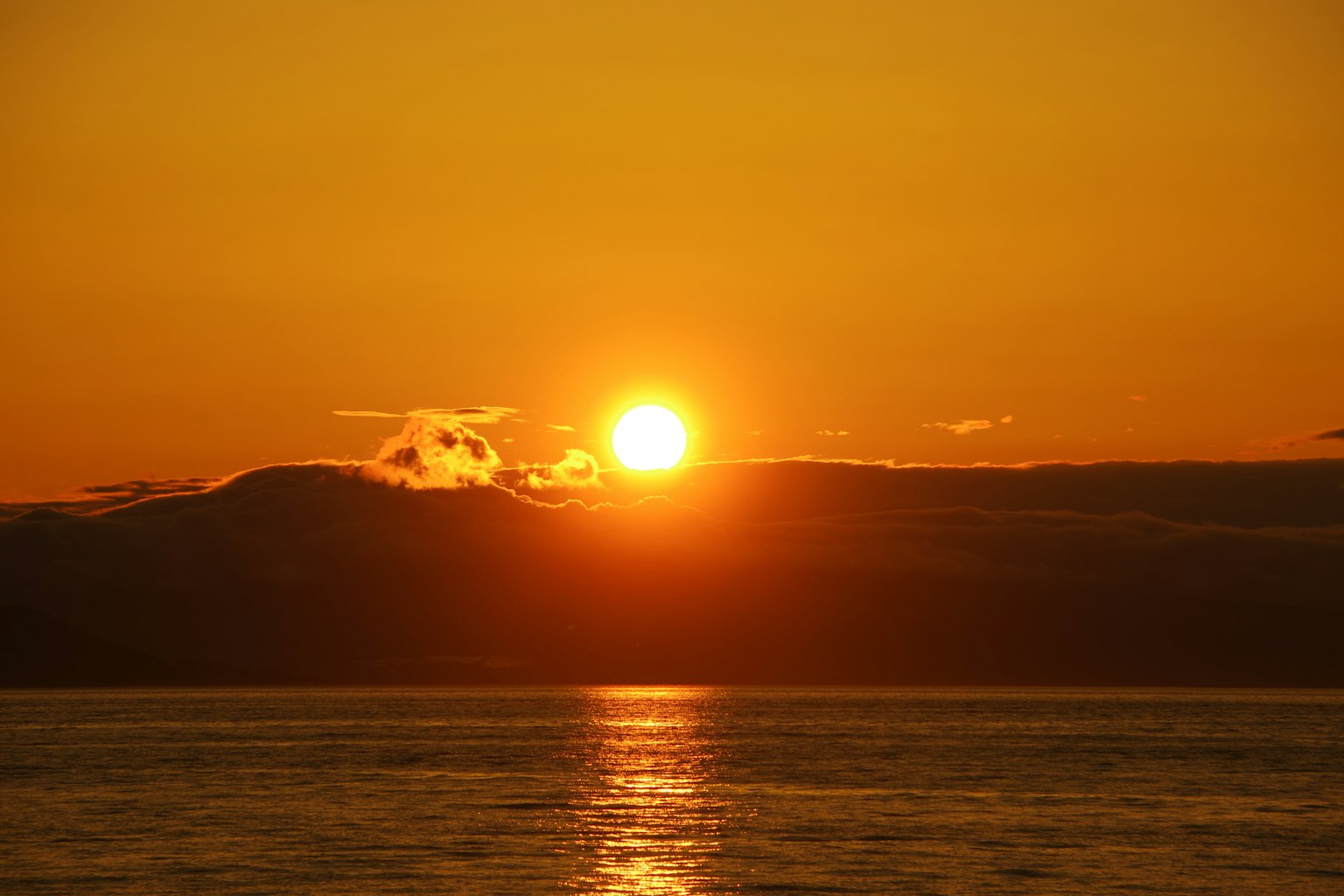 พระอาทิตย์ตกดินเหนือมหาสมุทรท้องฟ้าสีส้มและการสะท้อนบนผิวน้ำ