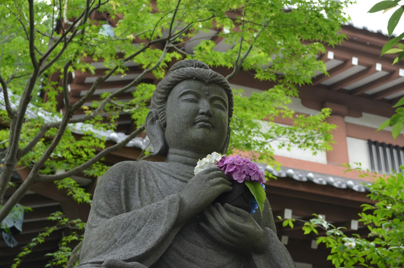 Une statue de Bouddha sereine tenant un bouquet entourée de verdure luxuriante