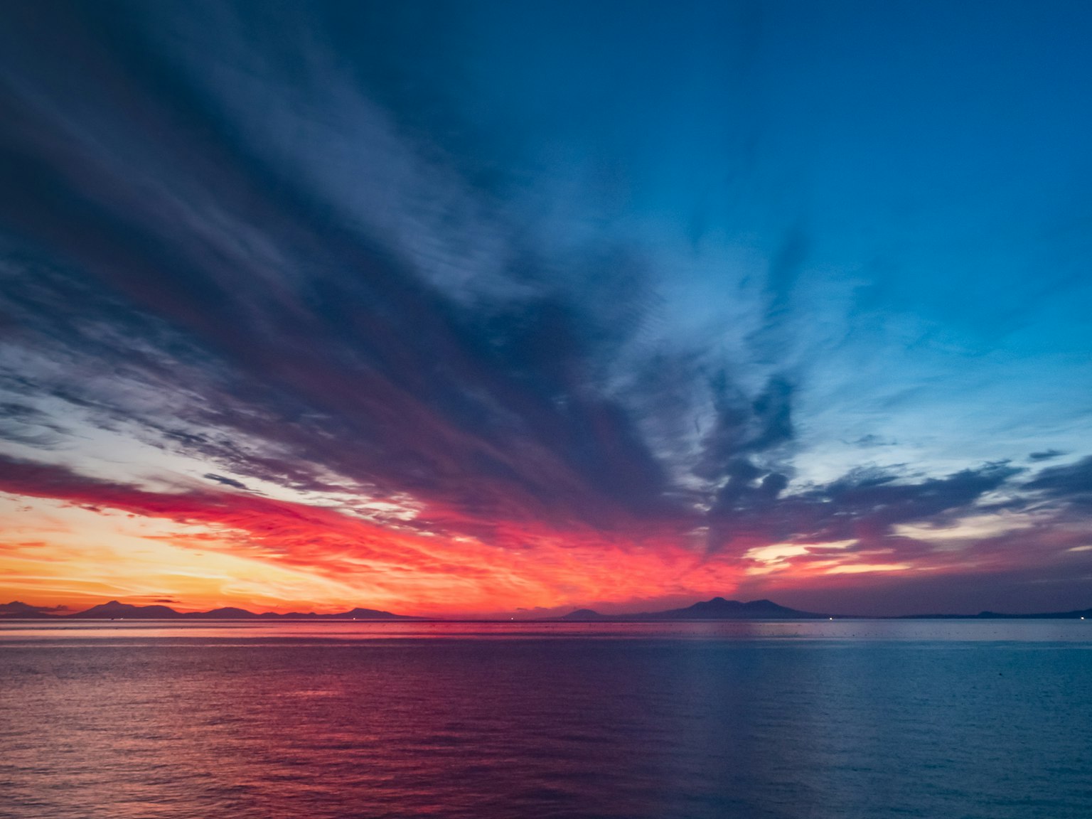 Beeindruckender Sonnenuntergang über dem Ozean lebendige Blau- und Rottöne