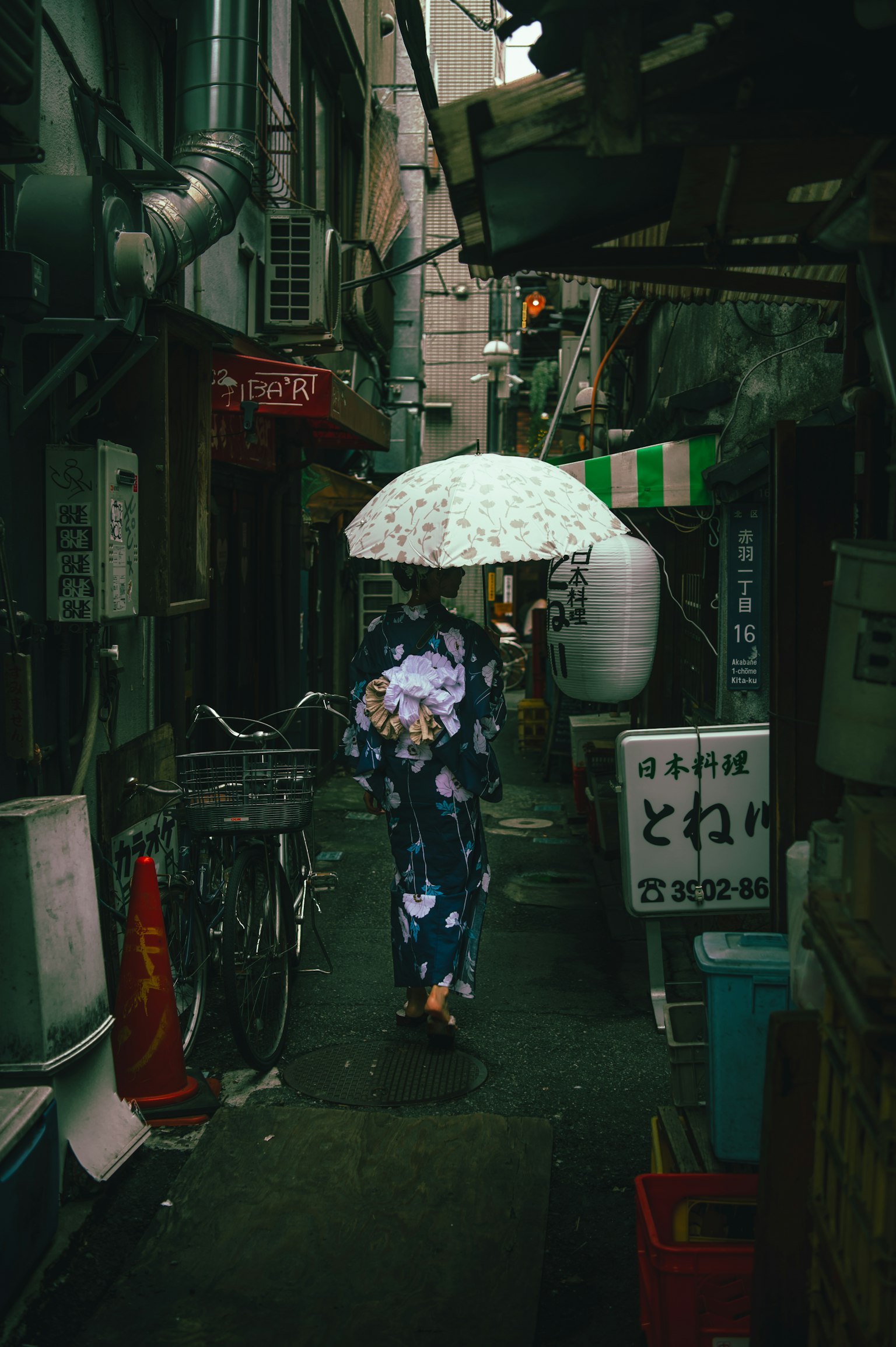 Woman in kimono walking in narrow alley with umbrella