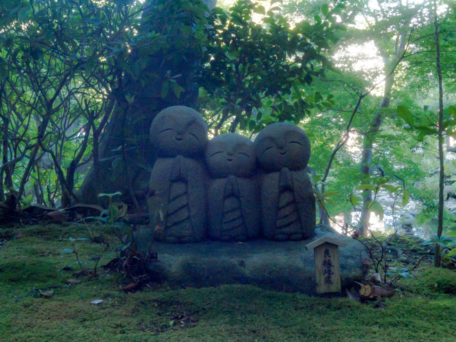 Escultura de piedra de tres caras en un entorno forestal
