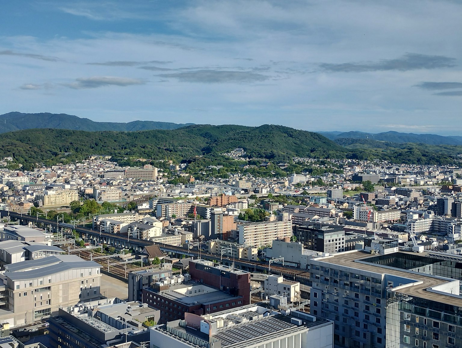 从高楼俯瞰城市的全景，背景有绿色山丘