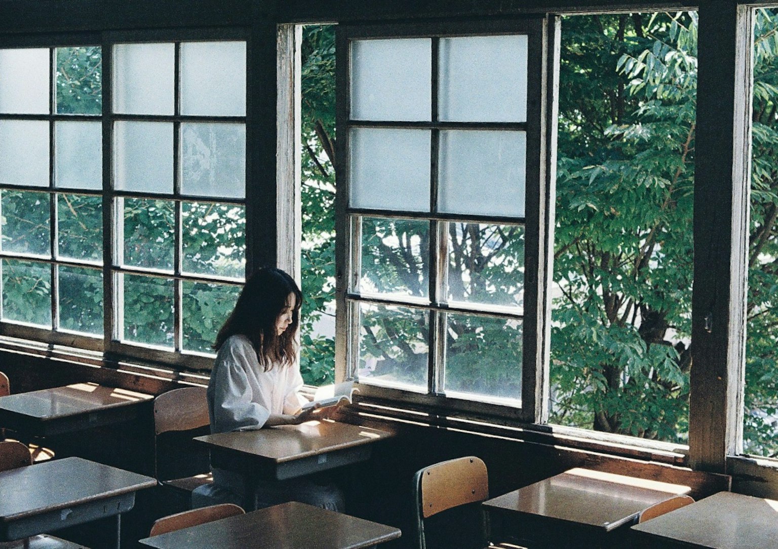Eine Frau sitzt in einem Klassenzimmer und schaut aus dem Fenster