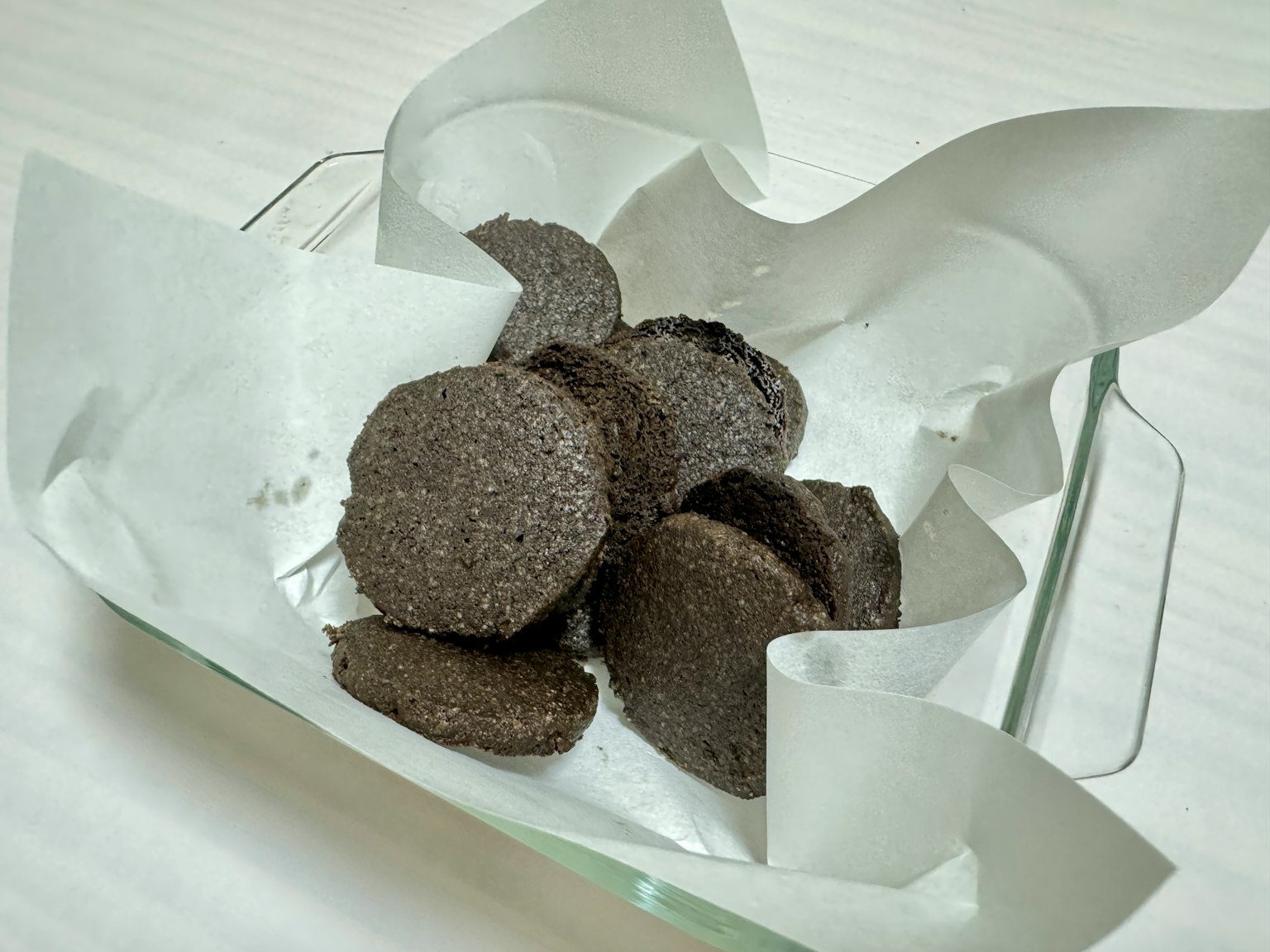 Un plato con galletas negras envueltas en papel pergamino blanco