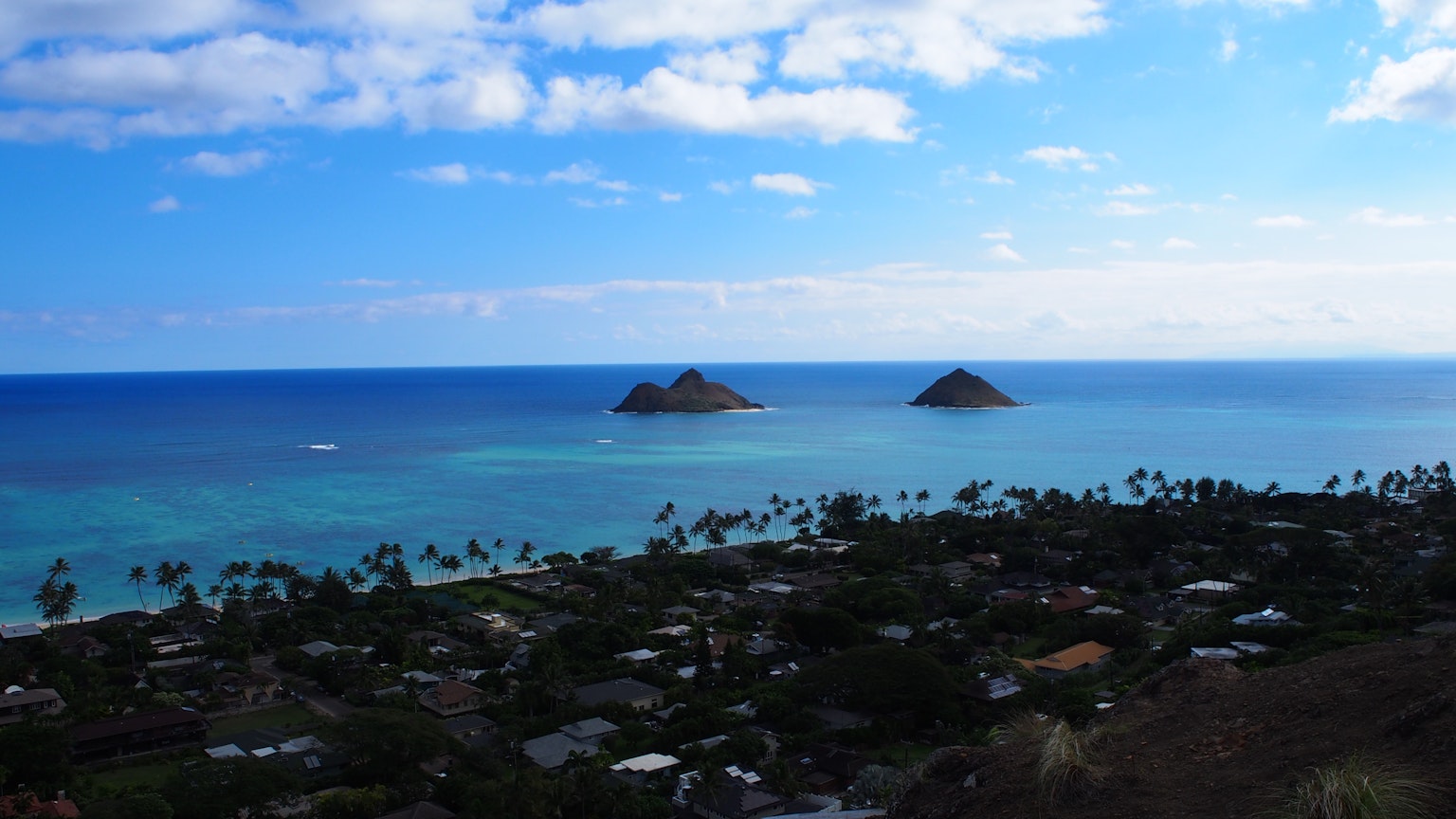 Scenic view of two small islands in blue ocean with a coastal town in Hawaii