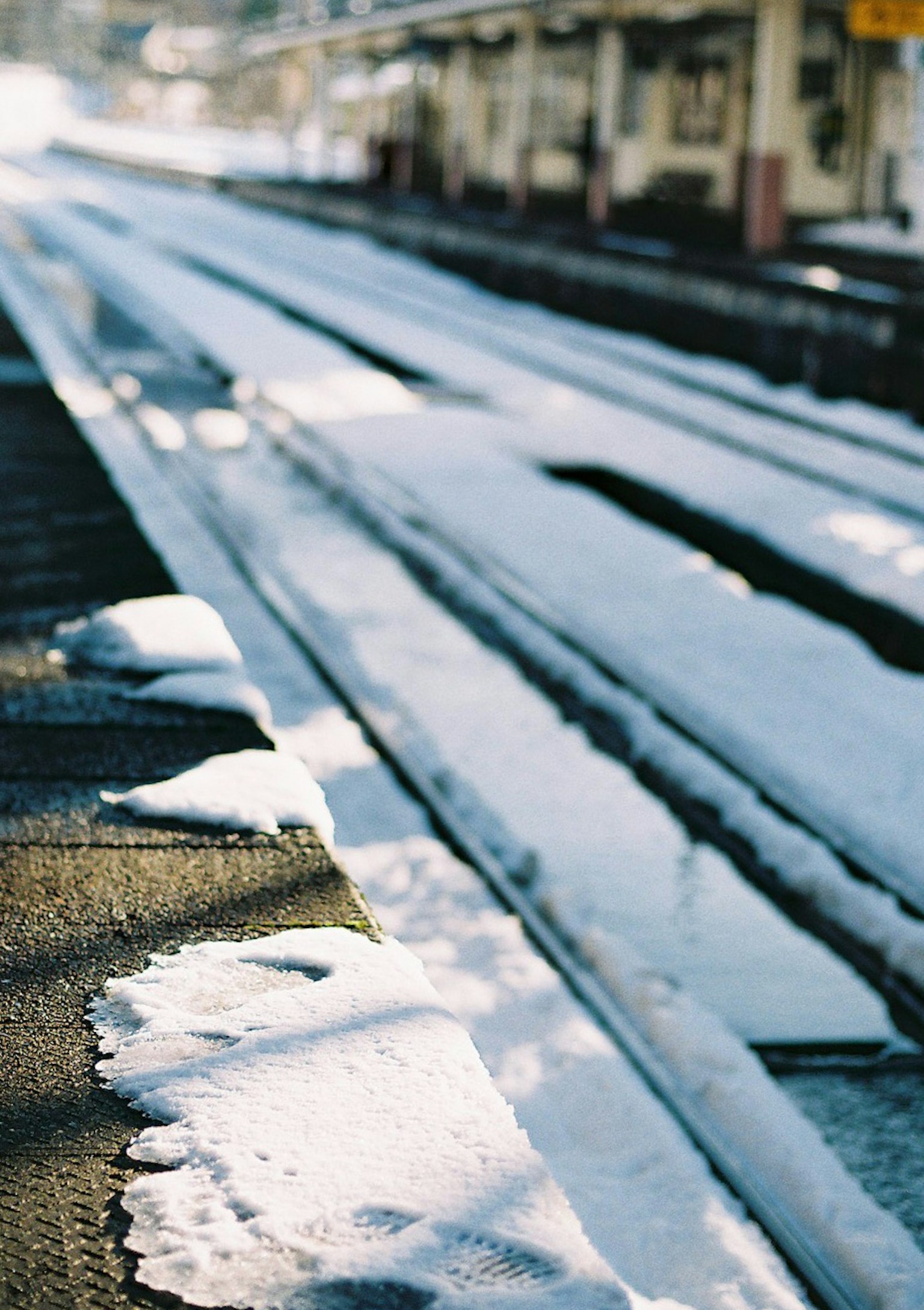 Lignes de chemin de fer couvertes de neige avec une gare à proximité