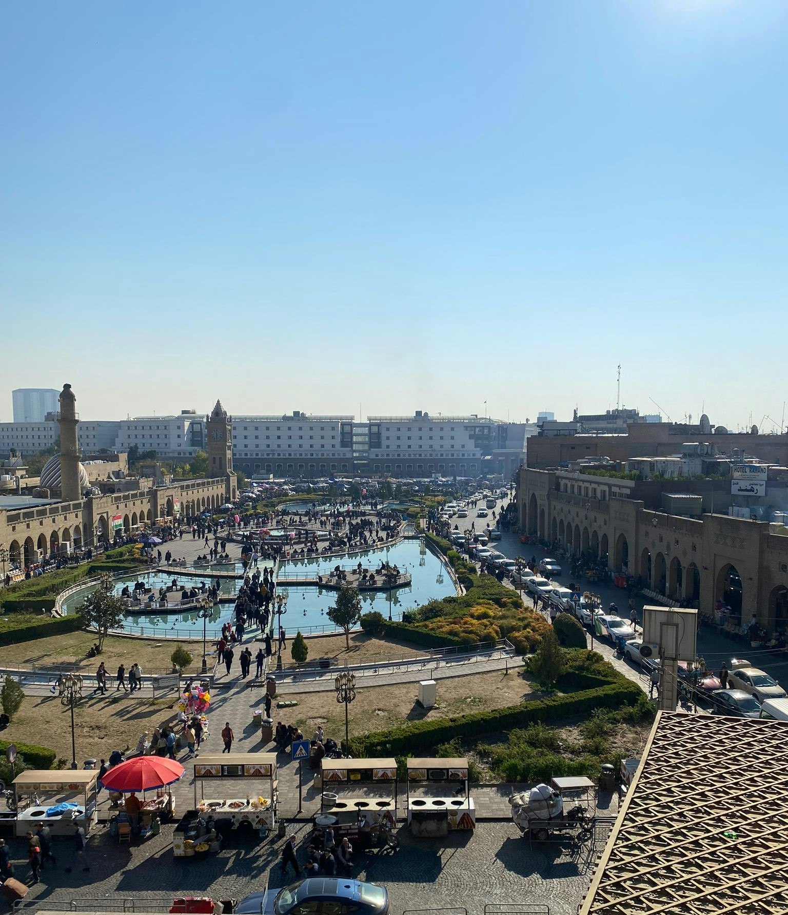 Una vista panoramica di un parco con un laghetto e molte persone riunite