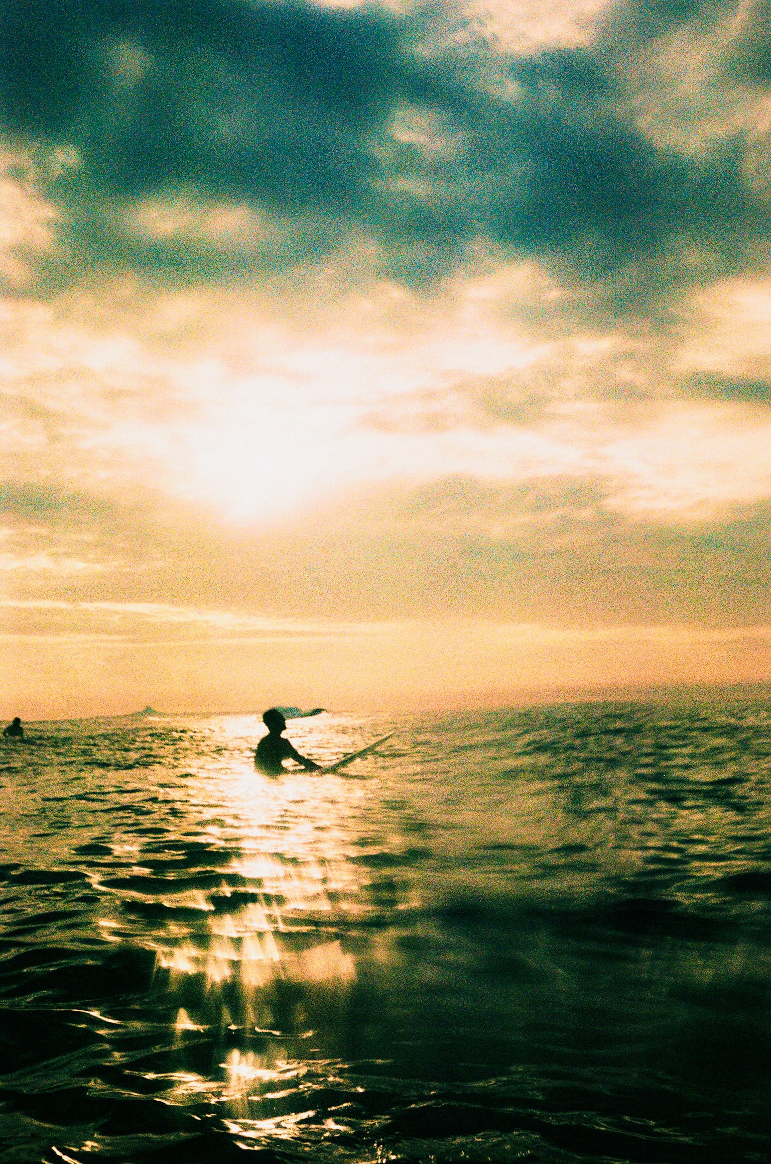 Silhouette di una persona che fa surf sullo sfondo di un tramonto