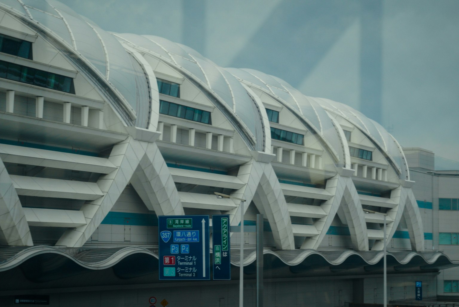 Esterno di un edificio aeroportuale futuristico con motivi di tetto lineari e segnaletica blu brillante