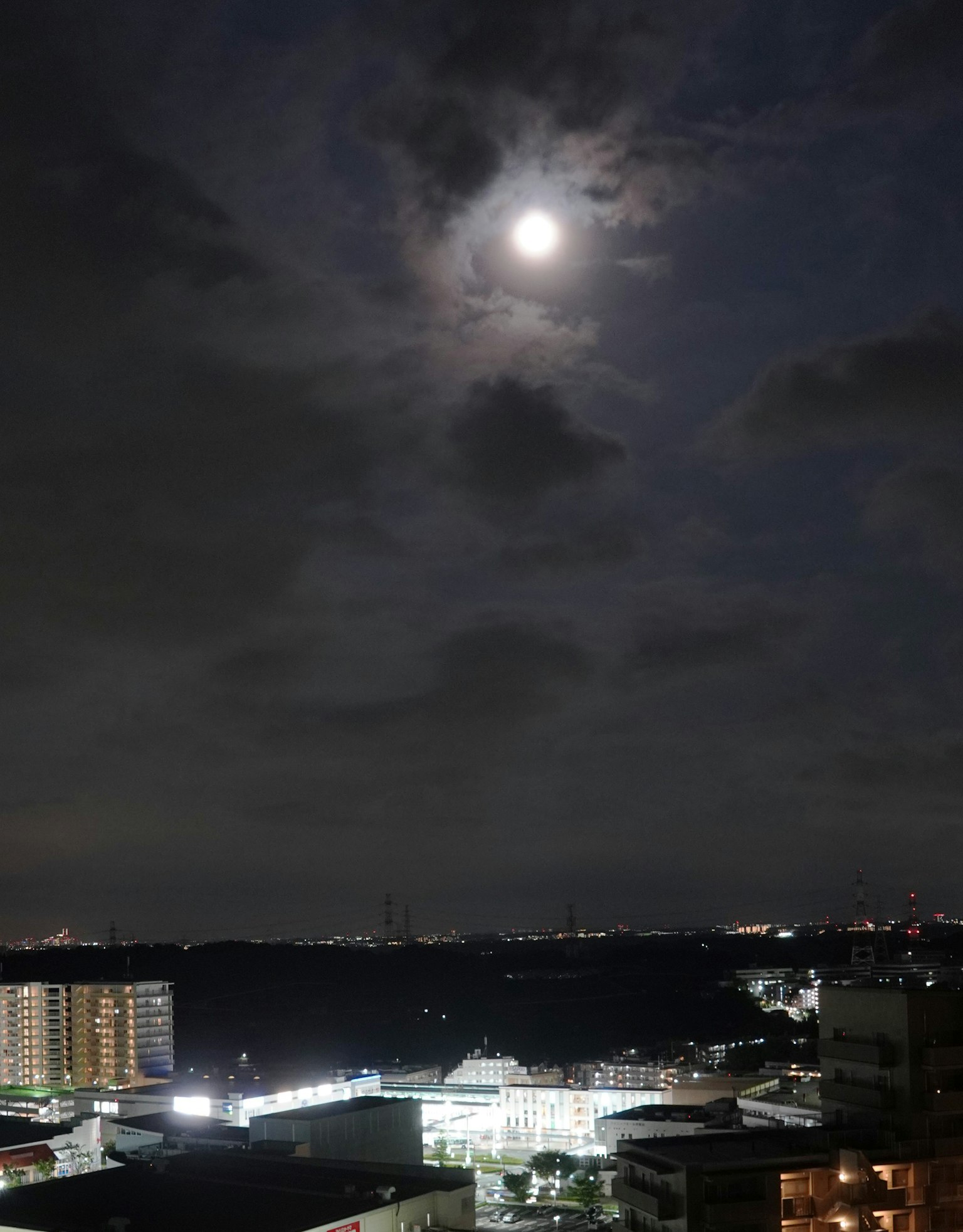 Ciel nocturne avec une pleine lune brillante et des nuages Paysage urbain avec des immeubles et des lumières de la ville