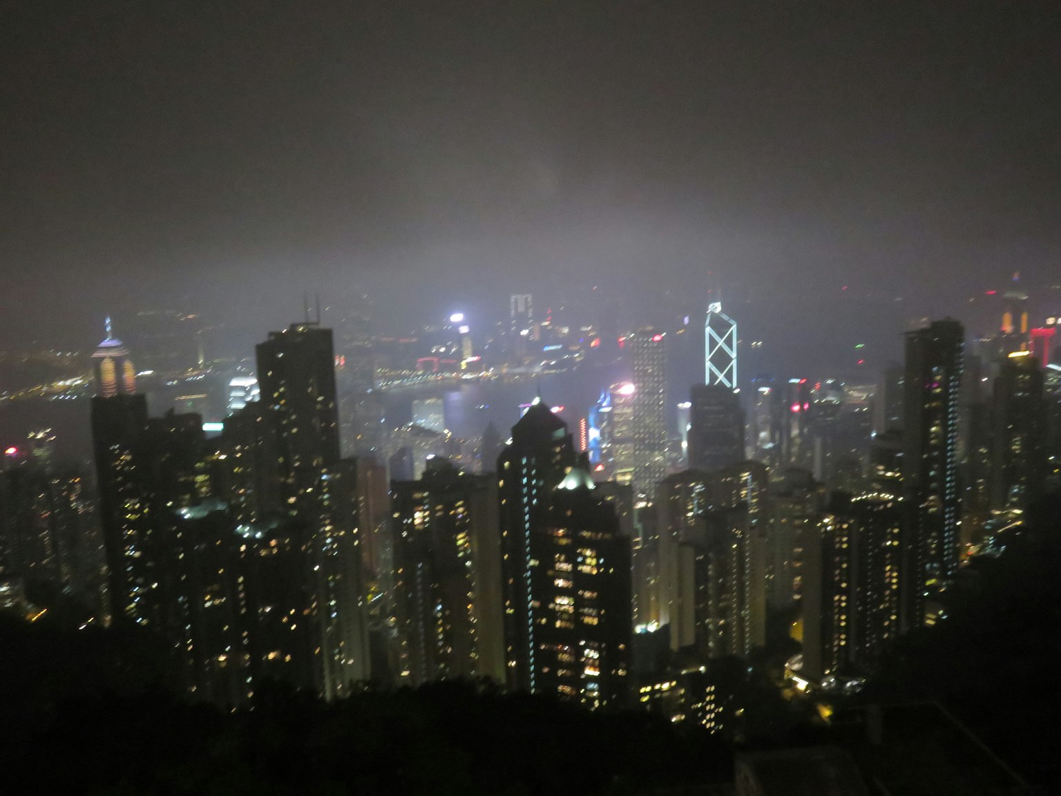 Vista nocturna de Hong Kong con rascacielos iluminados a través de la niebla