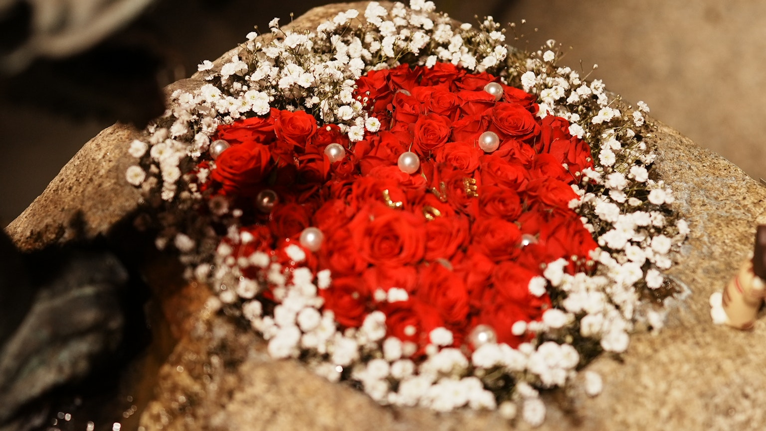 Heart-shaped arrangement of red petals and white decorations