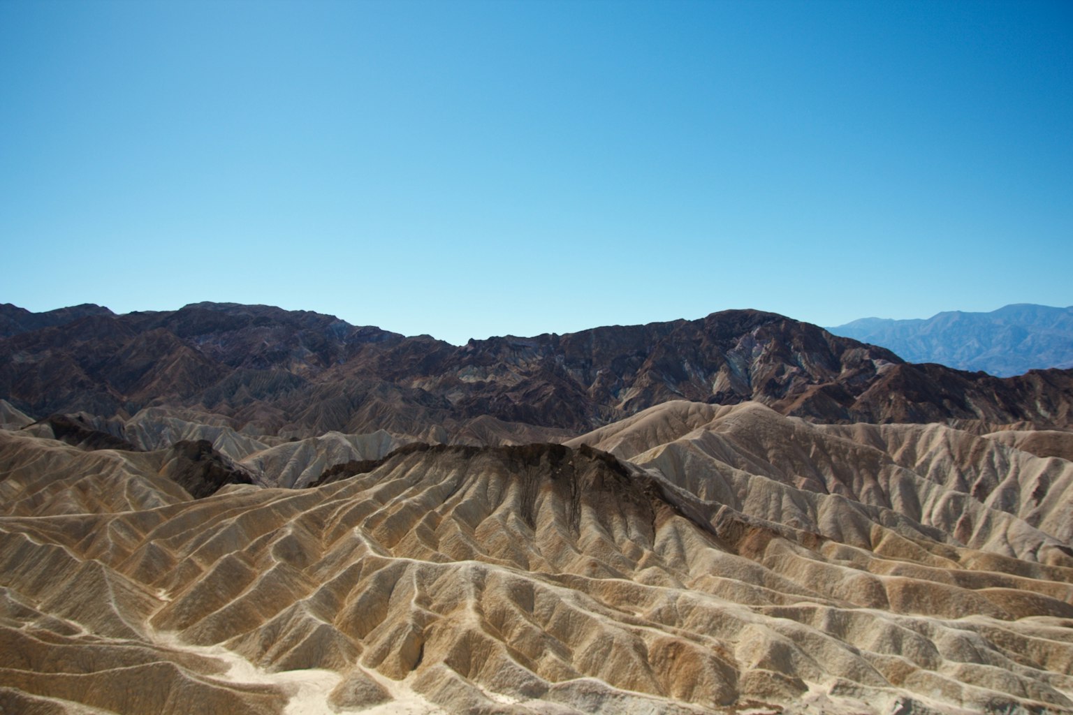 Duna pasir bergelombang di Death Valley di bawah langit biru cerah