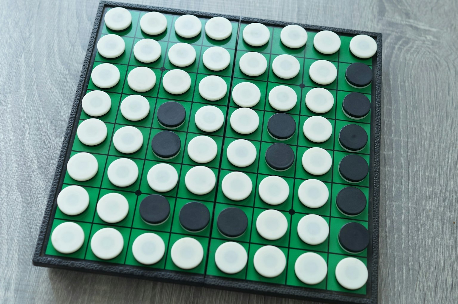 Plateau de jeu avec des pièces circulaires blanches et noires sur un fond vert