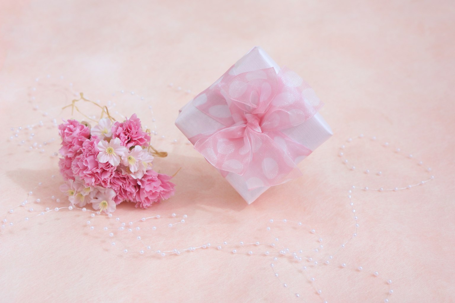 Sebuah bunga pink dan kotak hadiah putih di atas latar belakang lembut