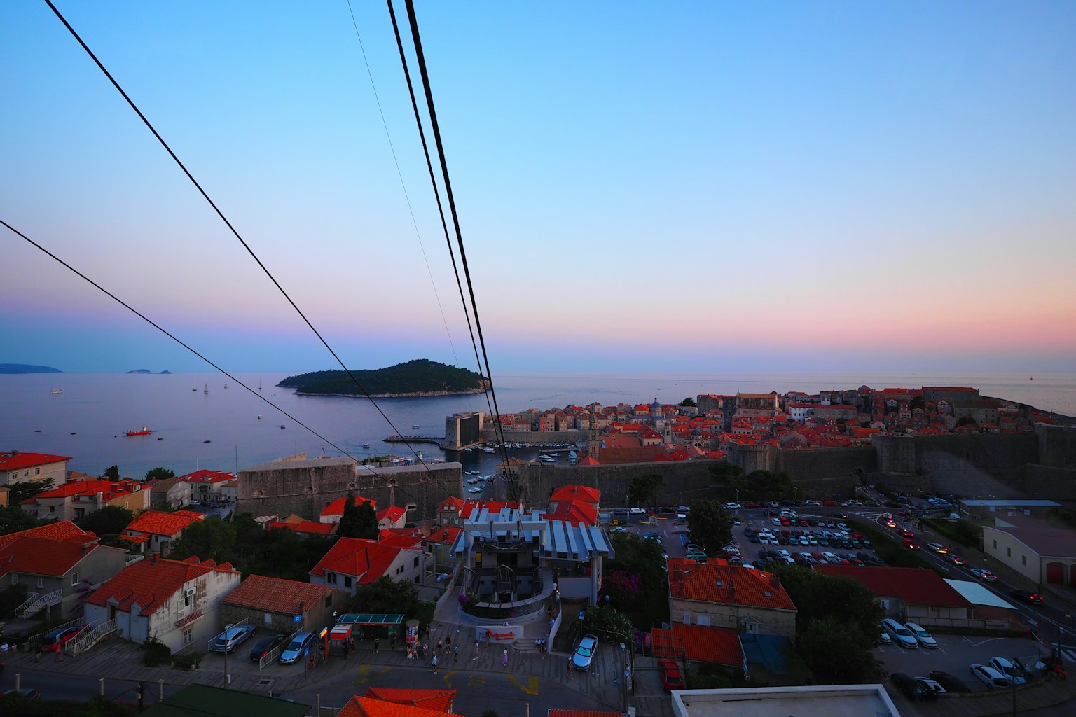 Hermosa vista del atardecer sobre el mar y el horizonte de la ciudad histórica con líneas de teleférico