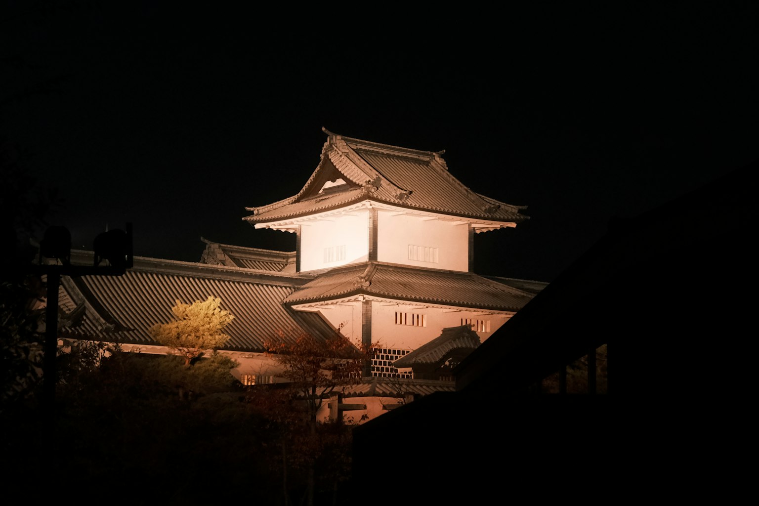 Beleuchtetes japanisches Schloss bei Nacht mit architektonischen Merkmalen
