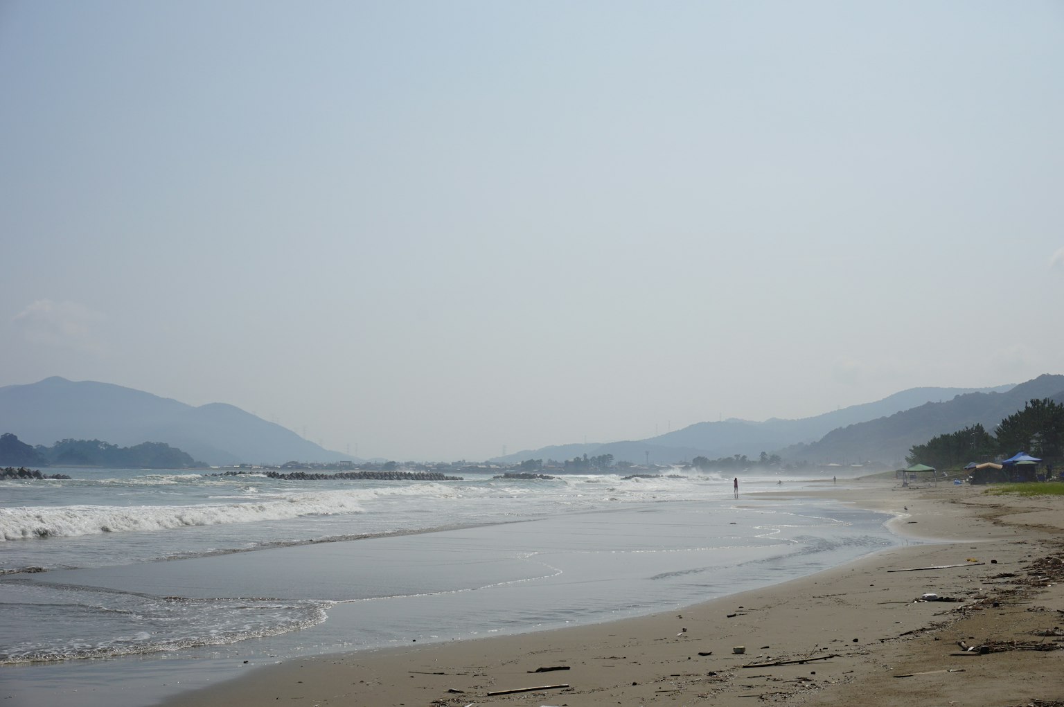 海滩的风景，海浪温和，远处有山脉