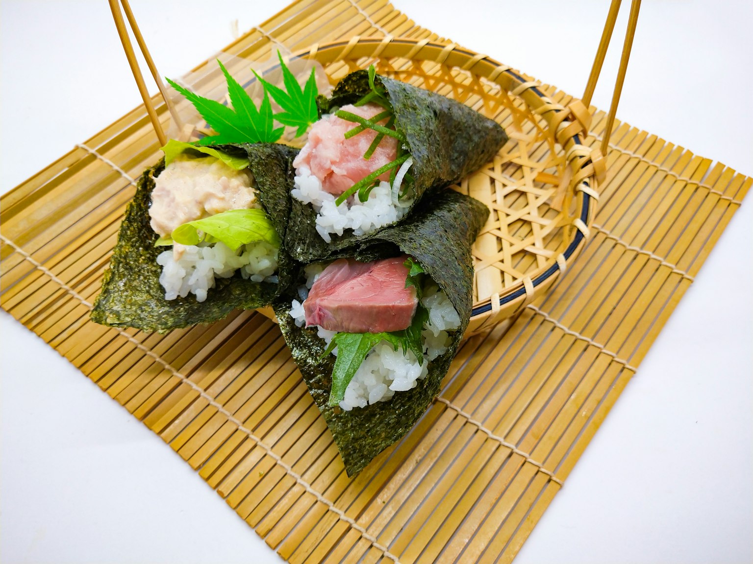 A basket containing beautiful sushi rolls placed on a bamboo mat