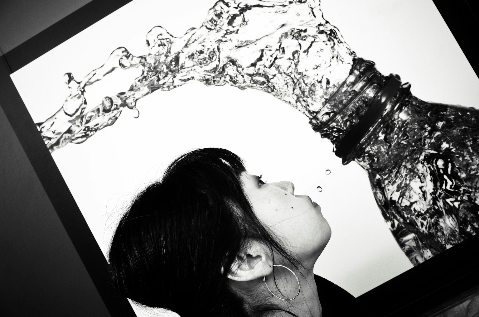 黑白照片展示一位女性喝水，液體從瓶子流出