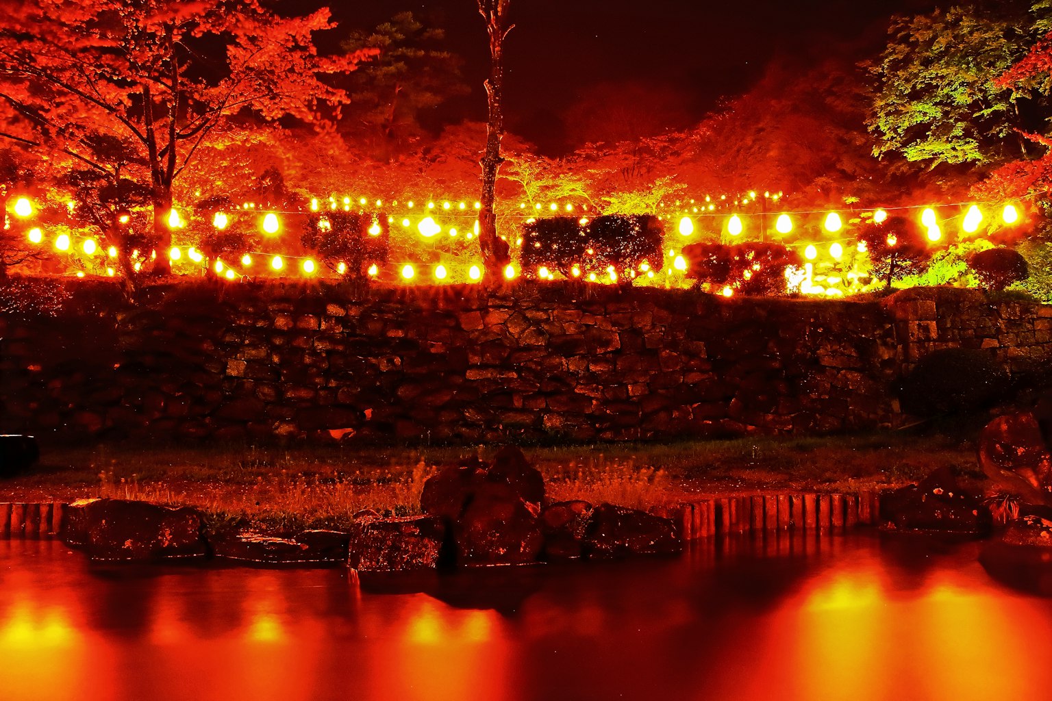 夜间花园中的橙色灯笼发光，水面上有反射