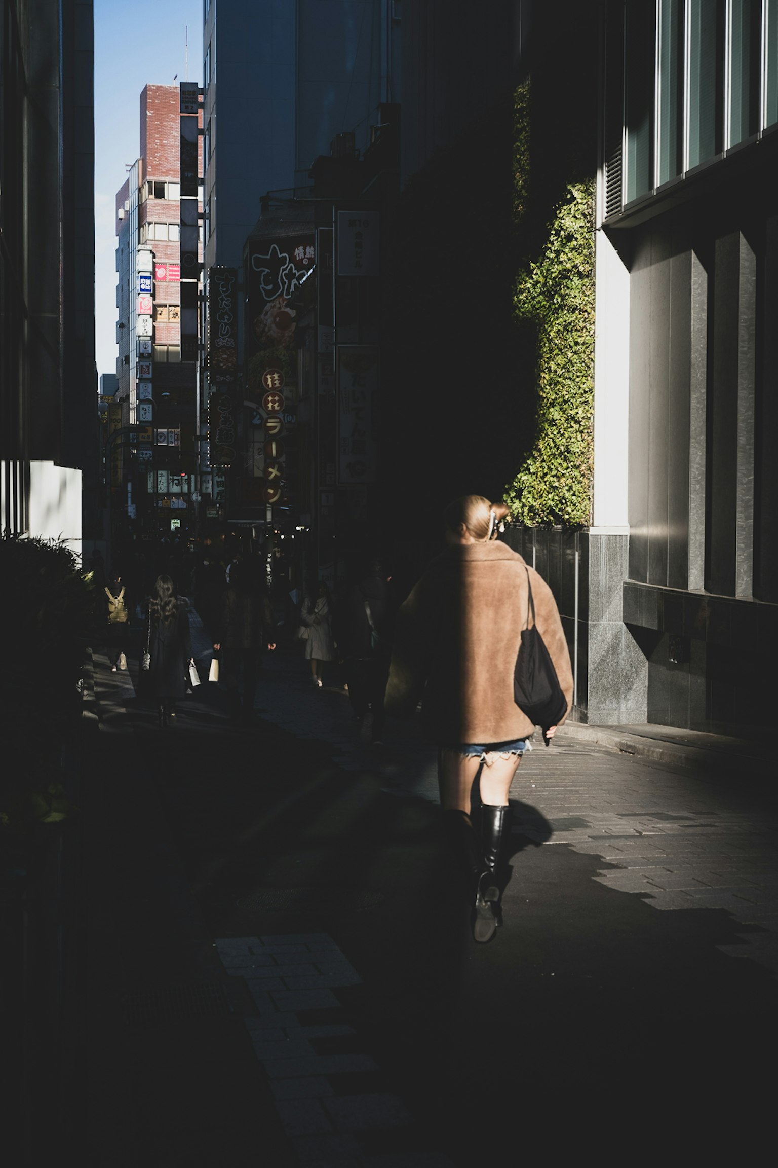 Una persona caminando en un callejón oscuro con sombras de edificios