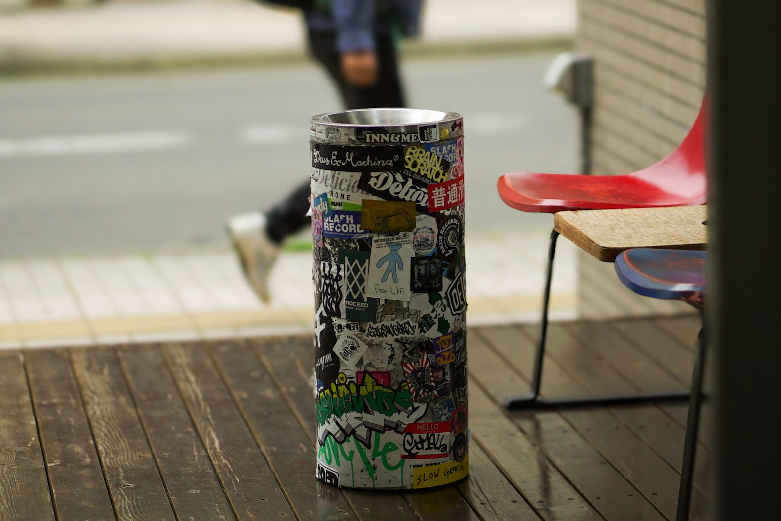 Une poubelle recouverte d'autocollants d'art de rue avec un piéton en arrière-plan