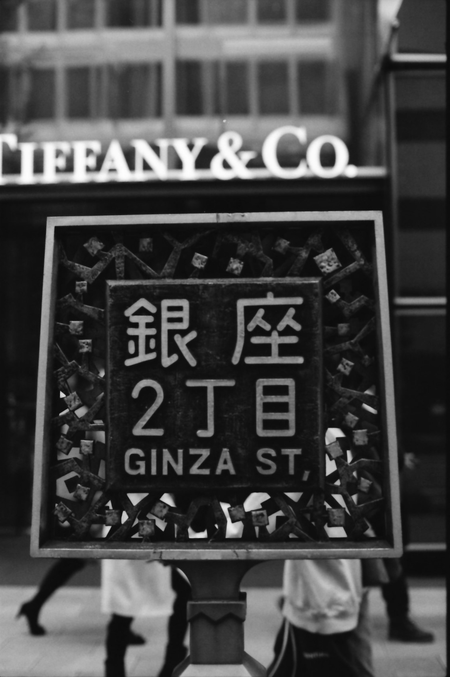 ภาพขาวดำของป้ายถนนในกินซ่าพร้อมกับ Tiffany & Co ในพื้นหลัง