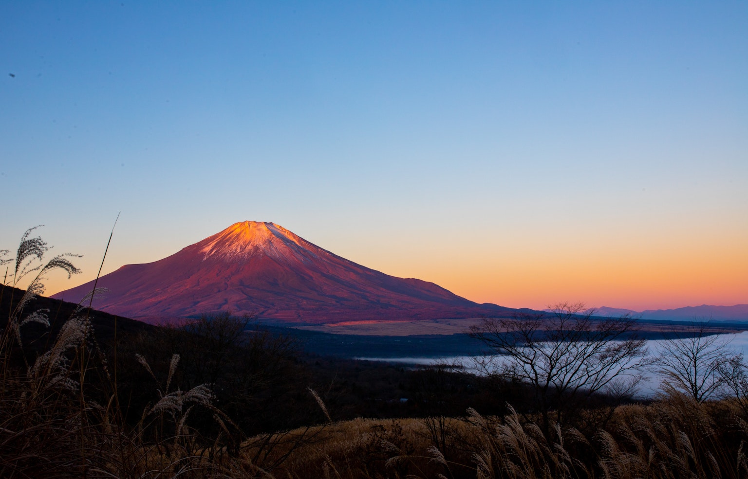 Magnifique vue du coucher de soleil sur le mont Fuji avec des couleurs vives et des nuages au premier plan