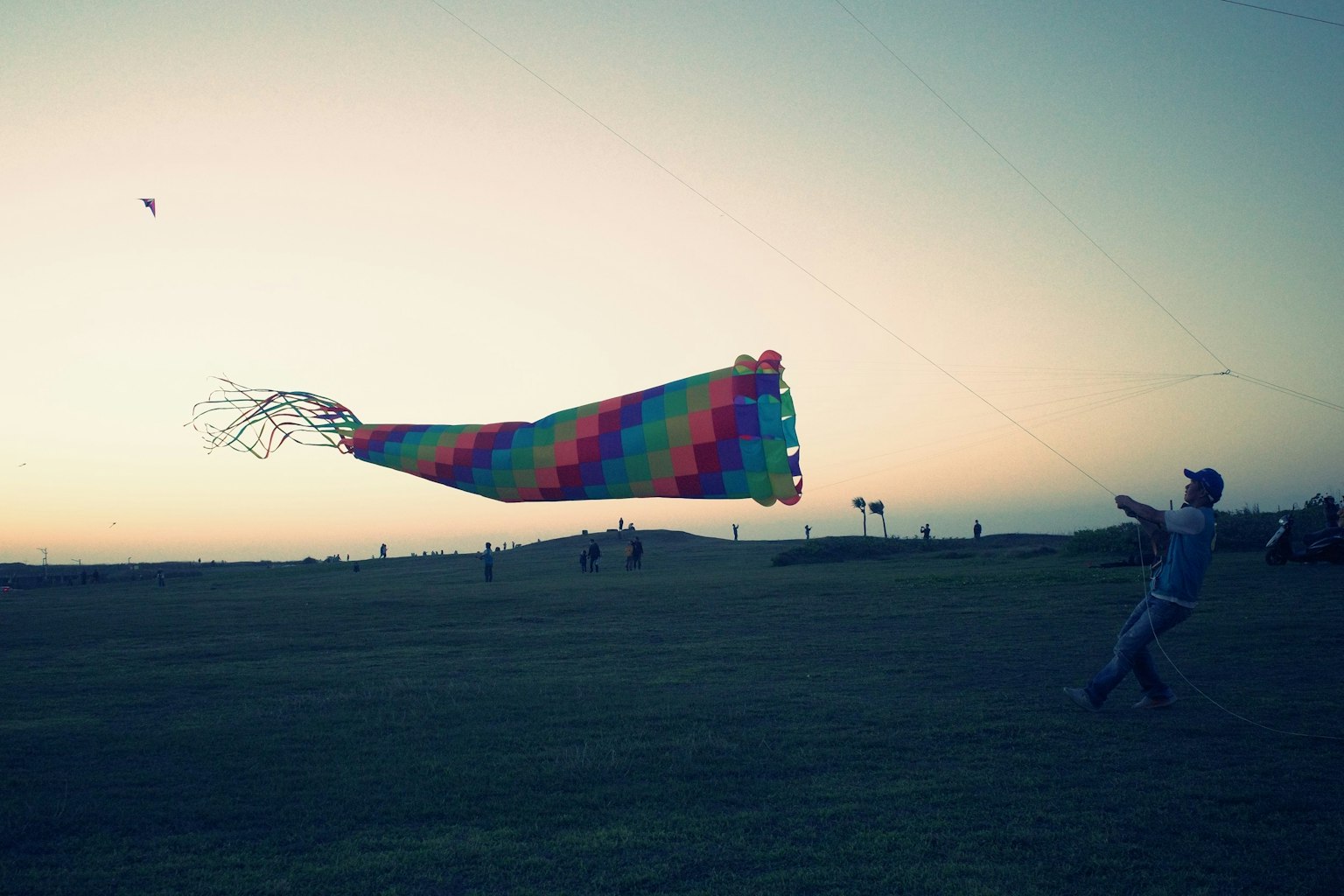 夕暮れ時にカラフルな凧を飛ばす人