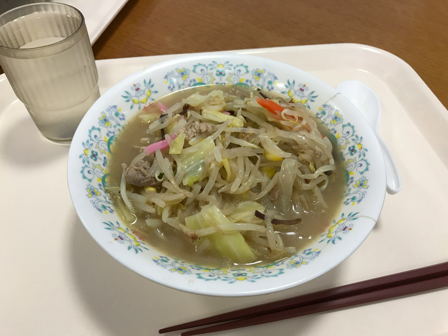 一碗盛有蔬菜和肉的湯，放在白色盤子裡