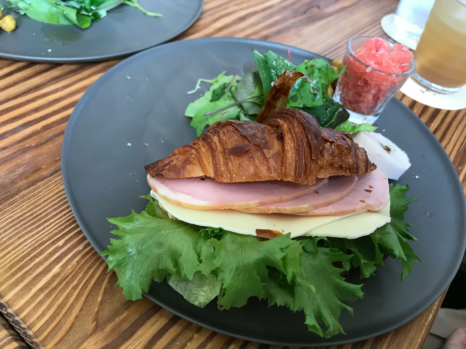 Sandwich au croissant avec jambon fromage et laitue sur une assiette noire