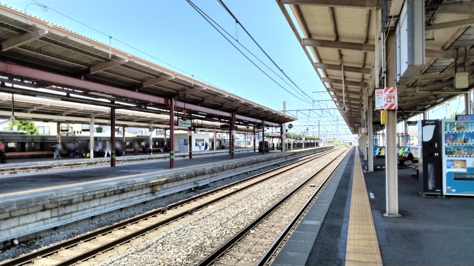 ชานชาลาสถานีรถไฟที่มีรางรถไฟมองเห็นได้และท้องฟ้าที่ปลอดโปร่ง