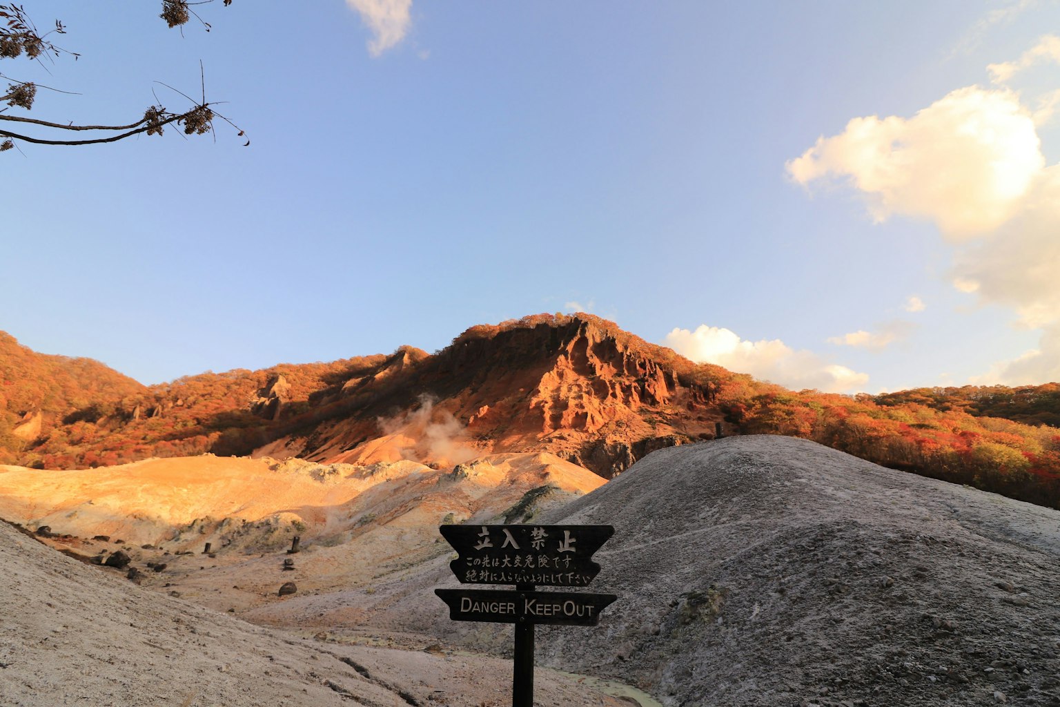 Pemandangan gunung dengan tanda yang menunjukkan sumber air panas