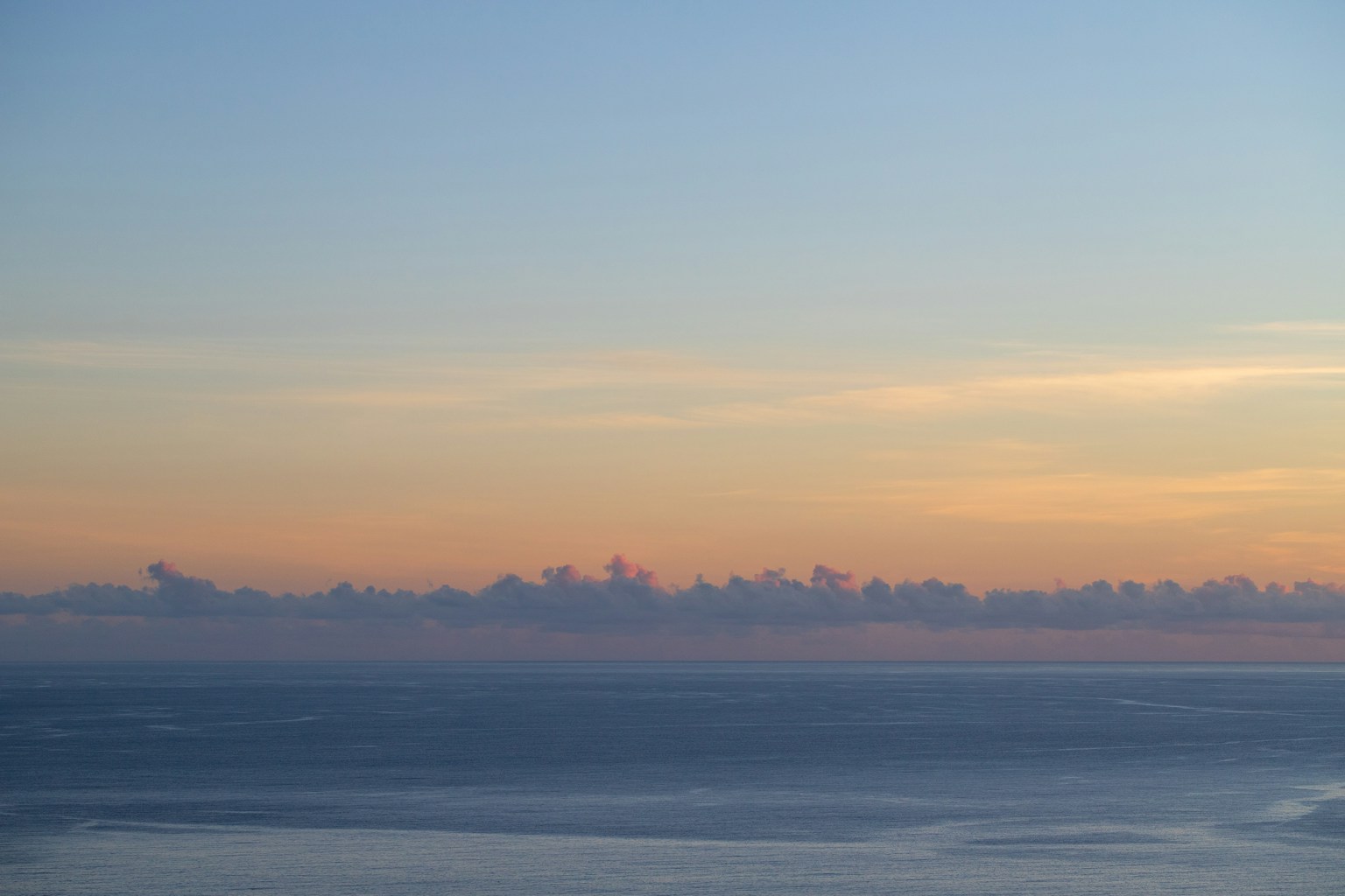 青い空とオレンジ色の雲が広がる海の風景