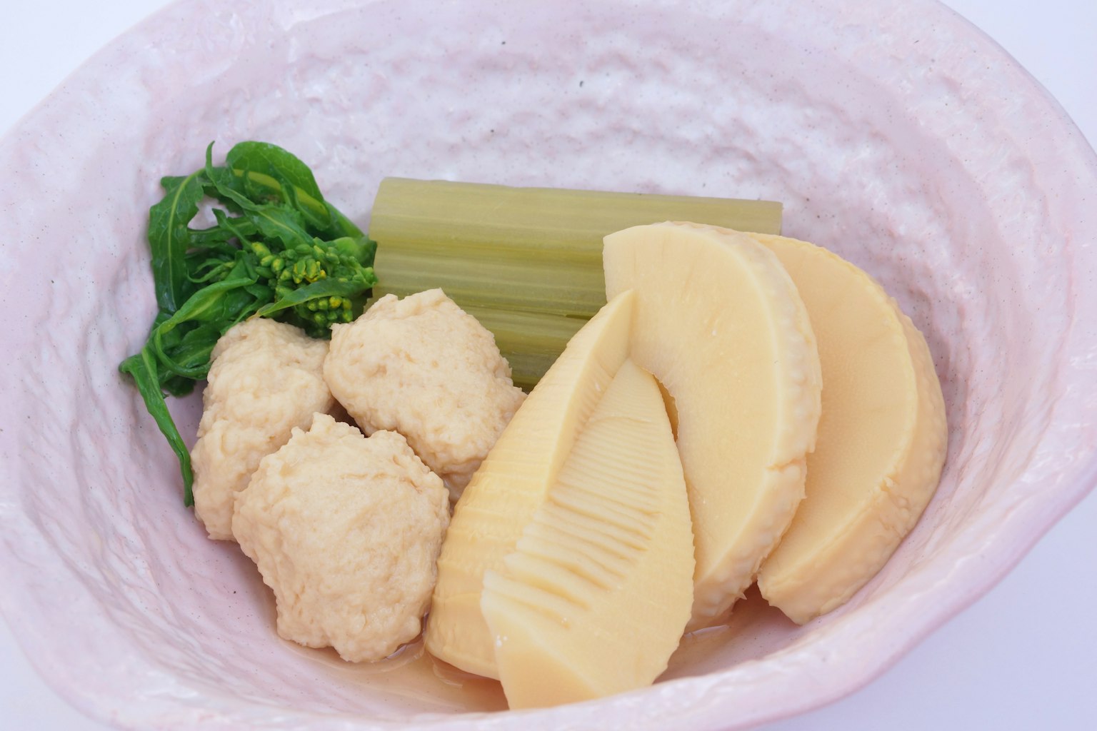 Tenere germogli di bambù e verdure verdi serviti su un piatto bianco con polpette rotonde