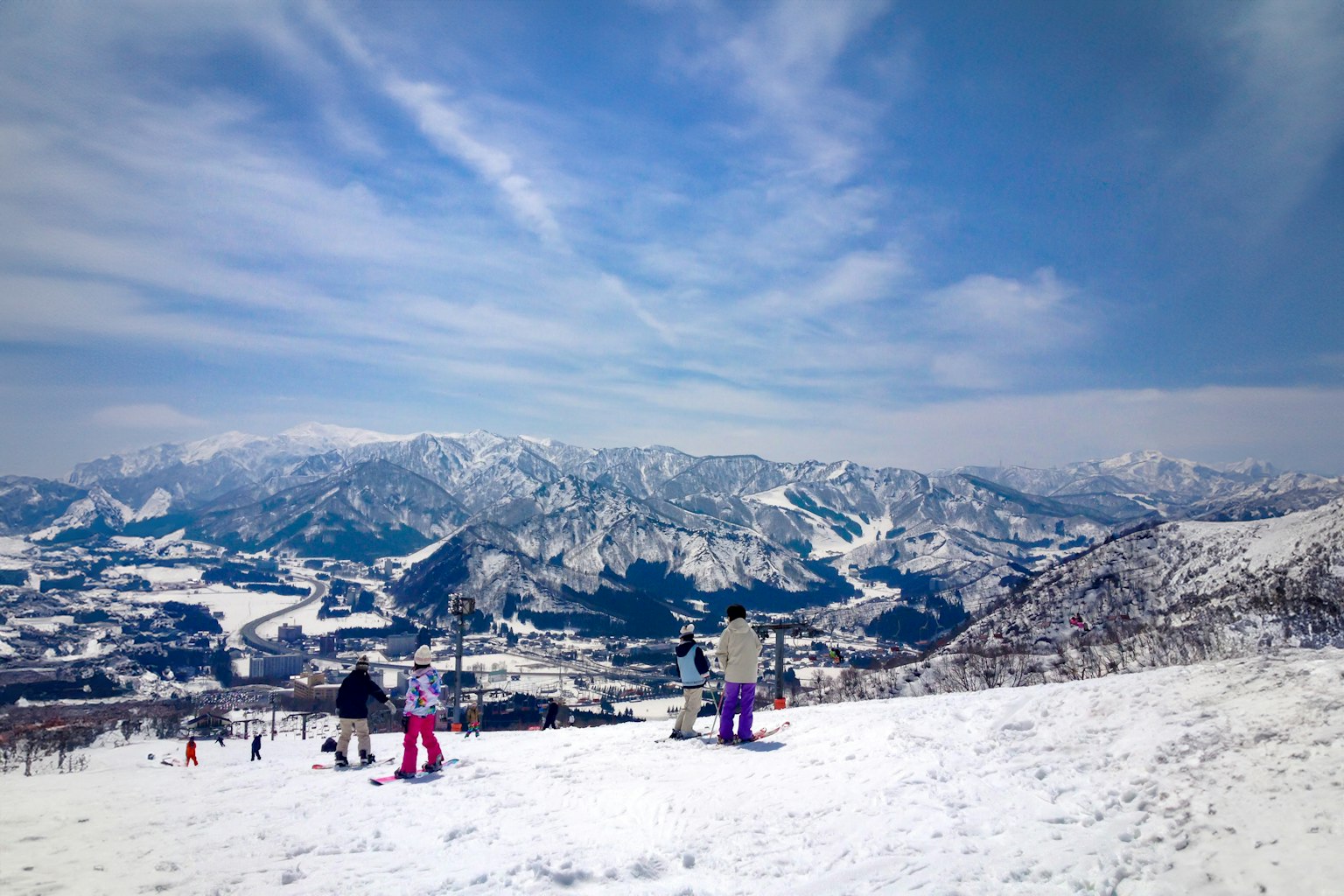 Skiers enjoying a snowy mountain landscape under a blue sky