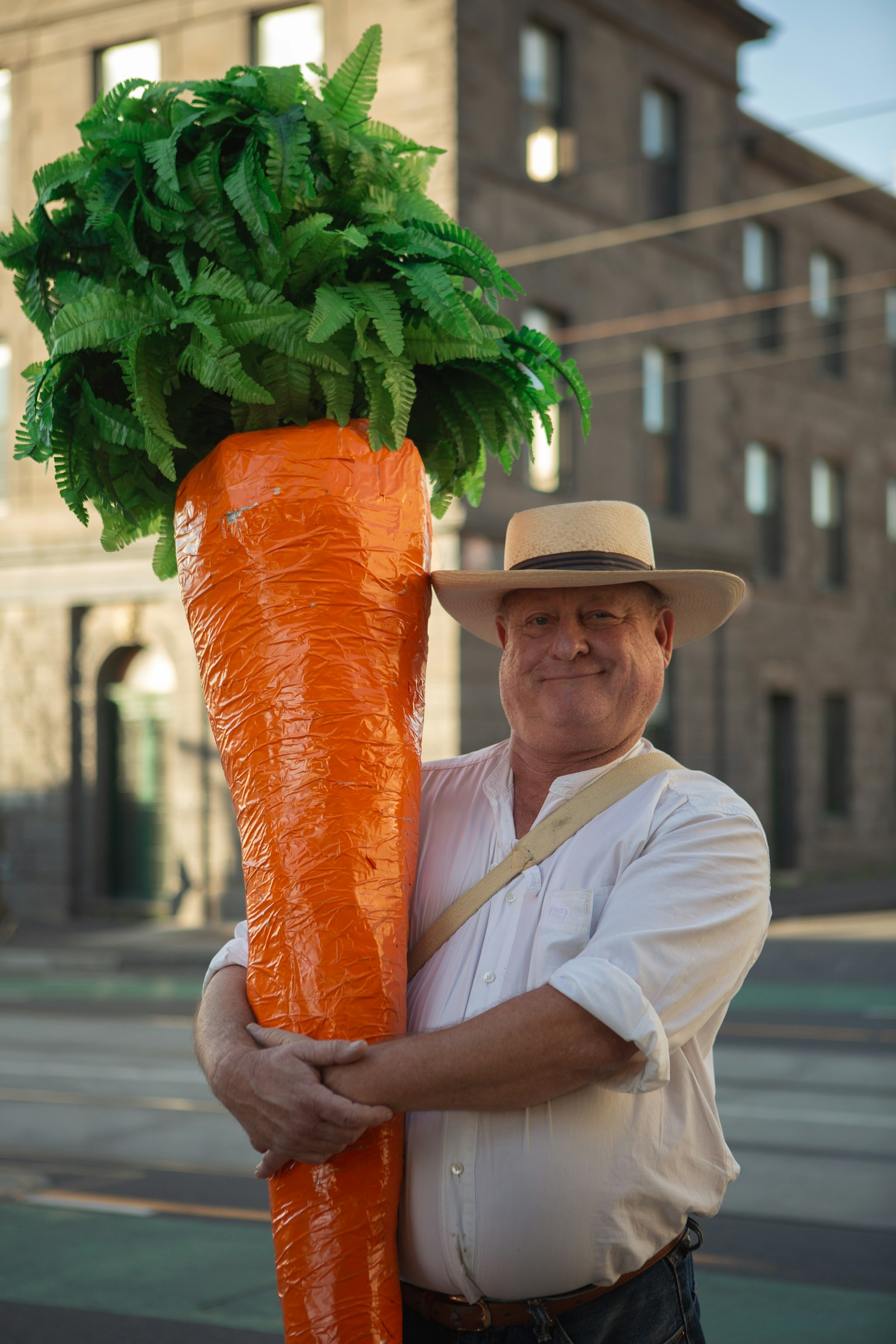 Man holding a giant carrot with green leaves