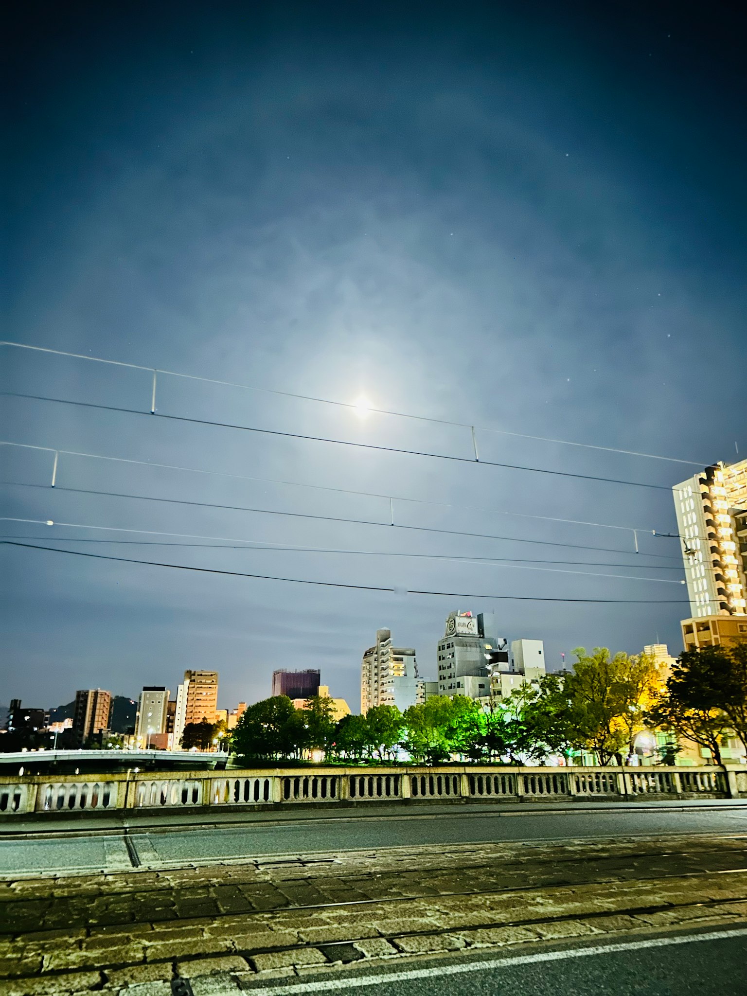 ทิวทัศน์เมืองในเวลากลางคืนที่มีพระจันทร์สว่างและเมฆ