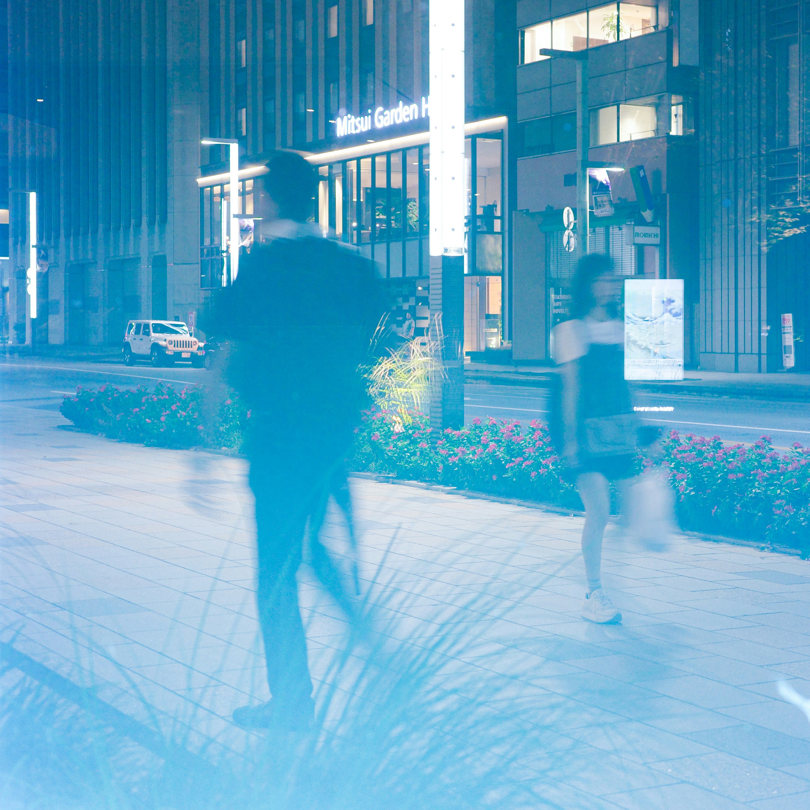 夜の東京の屋内外を行き交う人の残像と街灯のある通路