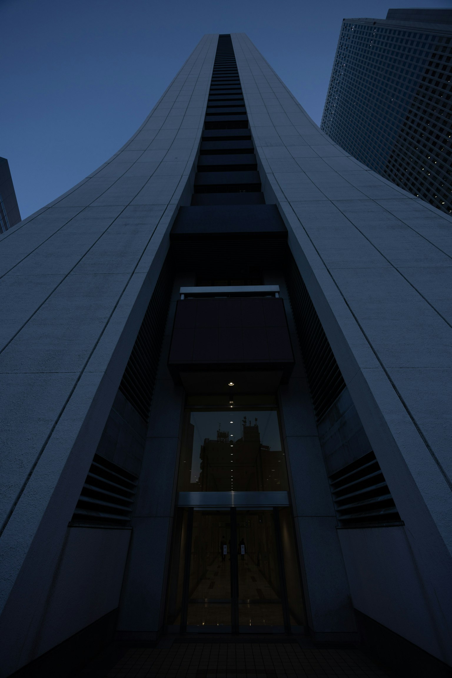 Vue nocturne de l'entrée d'un gratte-ciel mettant en valeur un design architectural unique et une forme