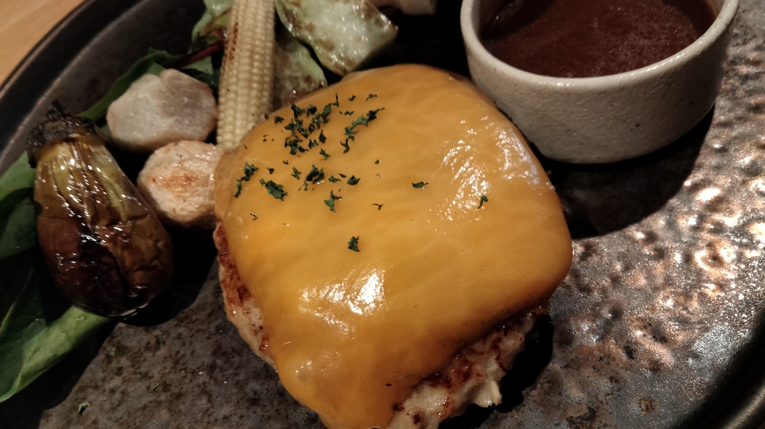 Burger au fromage surmonté de fromage fondu accompagné de légumes assortis