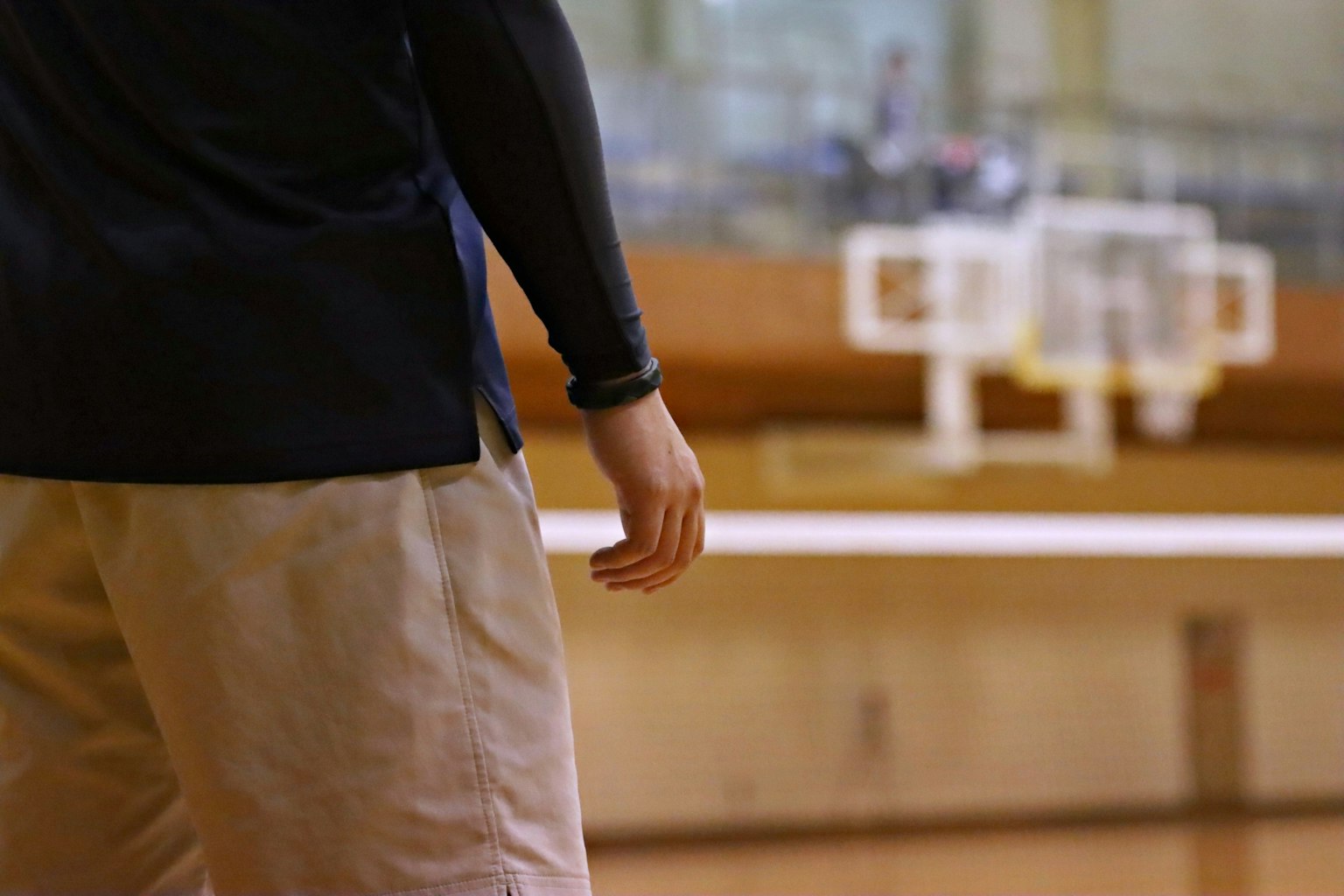 Seseorang berdiri di lapangan basket dengan tangan dan kaki terlihat