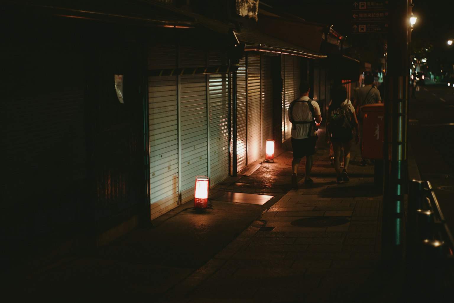 Des gens marchant dans une rue faiblement éclairée avec des lanternes la nuit