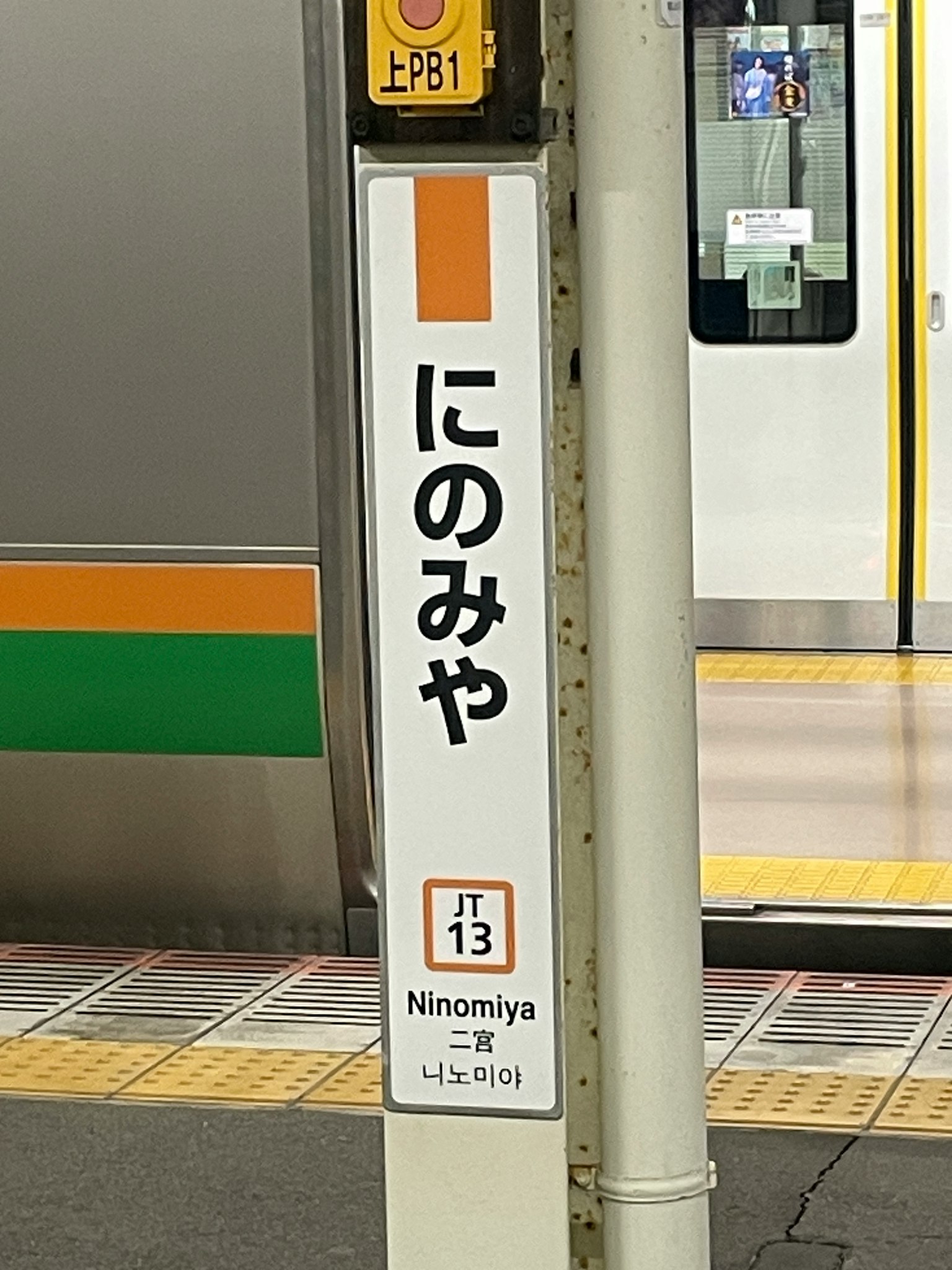 ป้ายสถานีนิโนมิยะพร้อมส่วนของรถไฟที่มองเห็นได้
