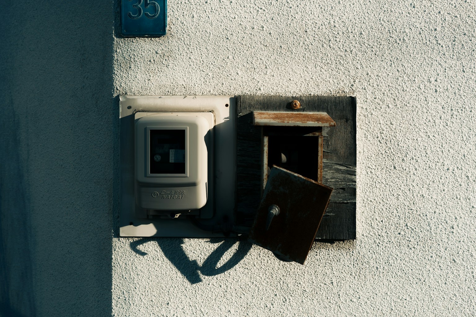 Alte Briefkasten und Stromzähler an einer weißen Wand montiert