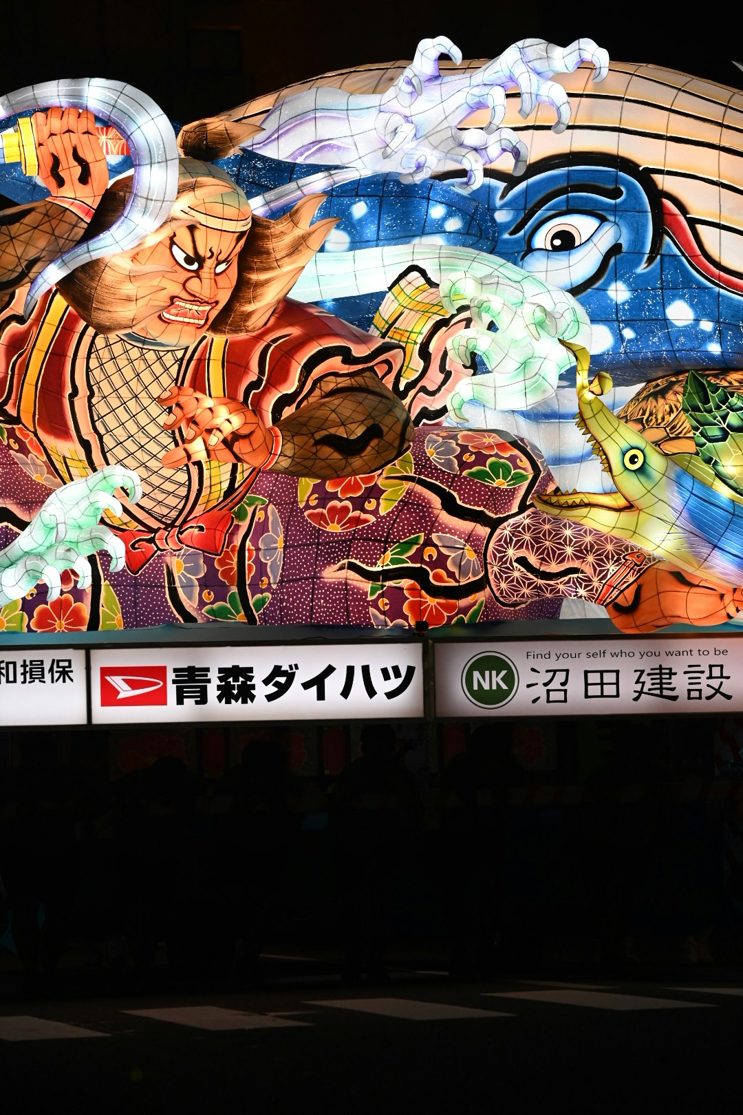 青森ダイハツの看板前に描かれた和風キャラクターの巨大壁画