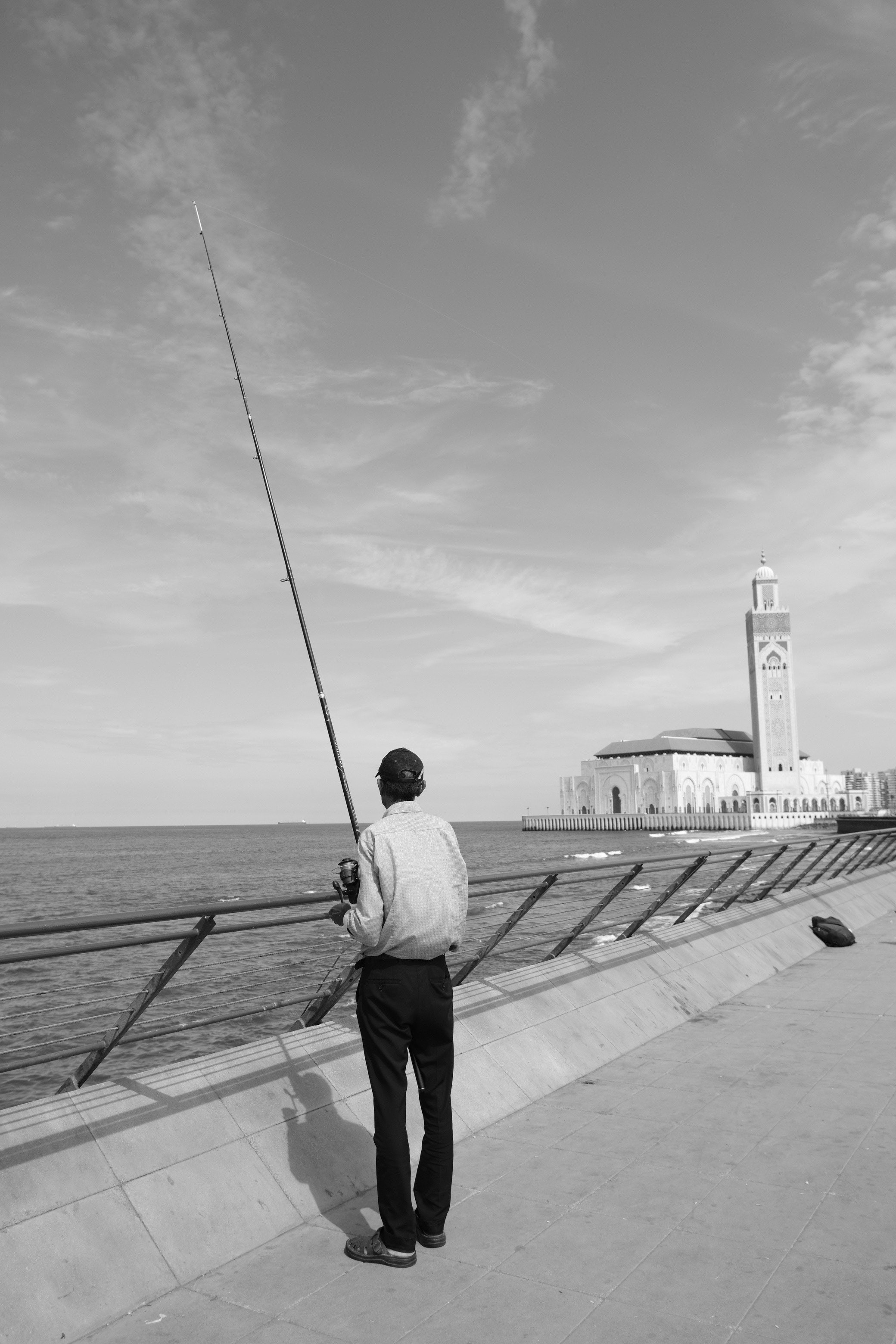 海辺の防波堤で釣りをする人と釣り竿のある風景
